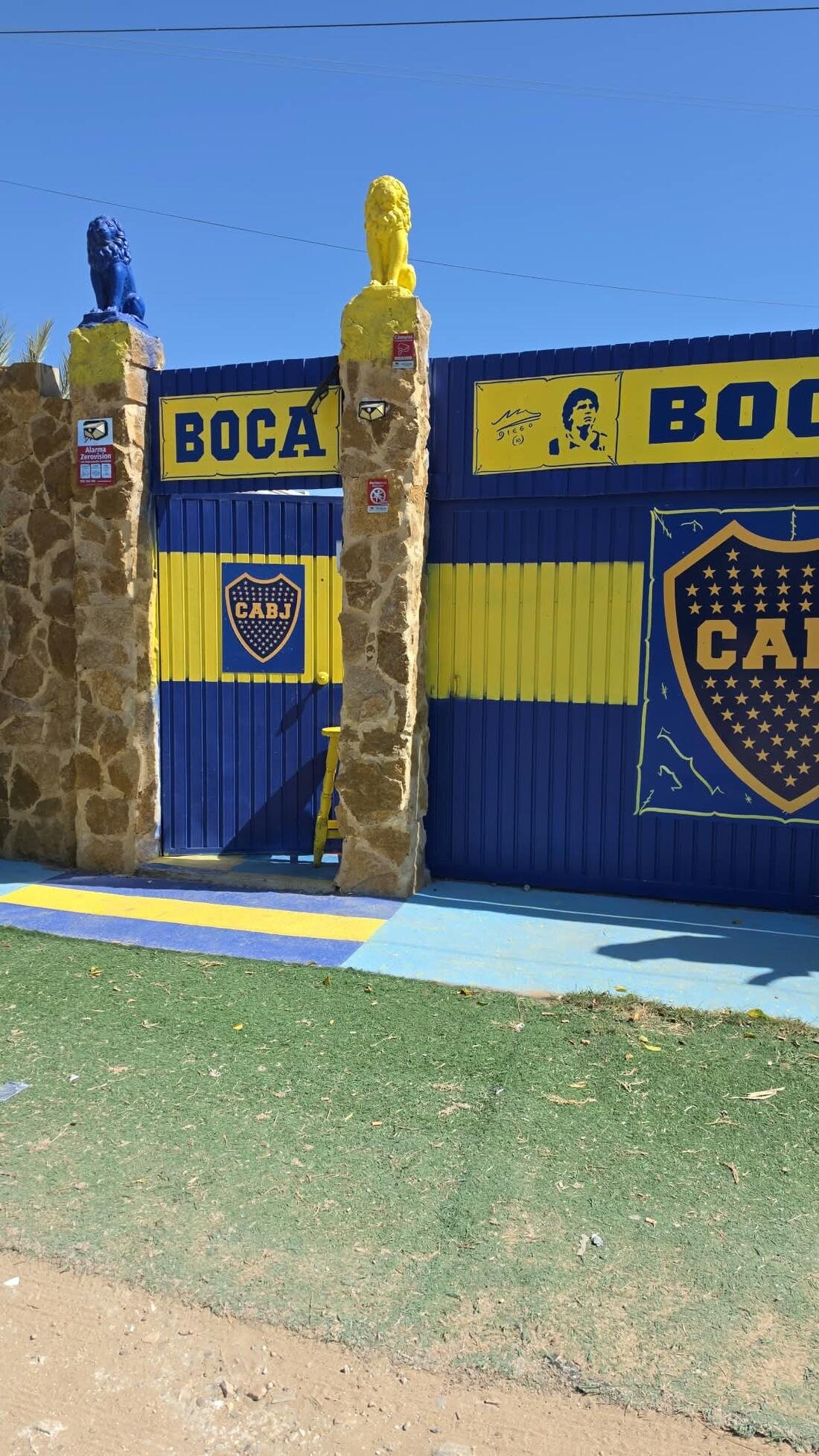 Entrada de Casa Xeneize, con leones y portones azules y amarillos